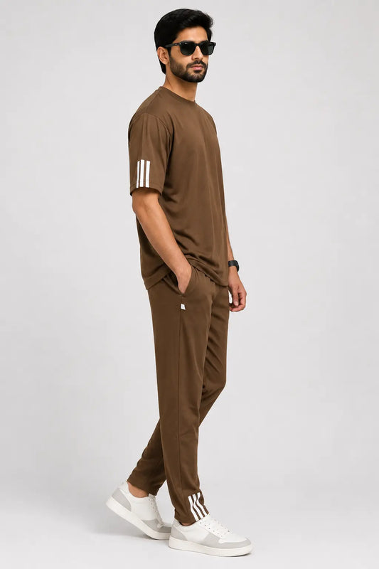 Man wearing a brown outfit with white stripes and white sneakers on a light gray background