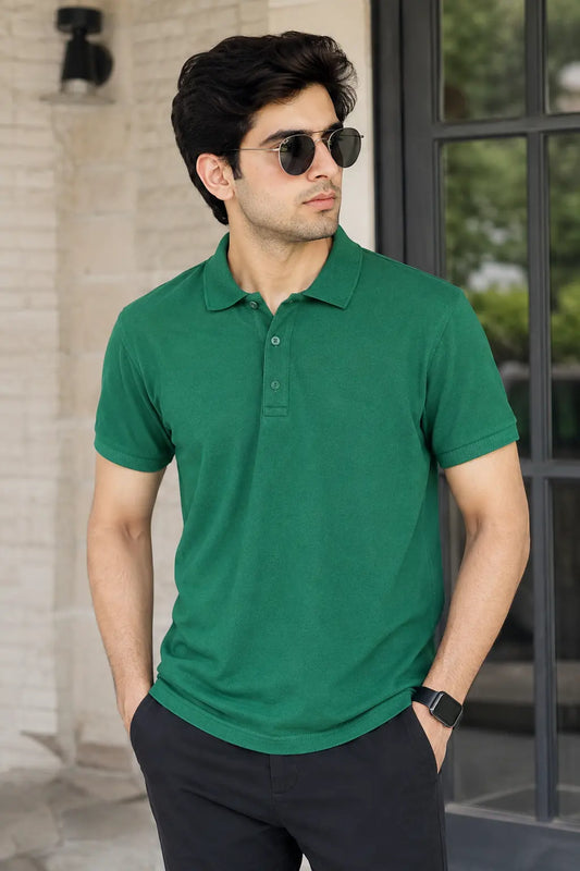 Man wearing a green polo shirt and sunglasses standing outdoors.