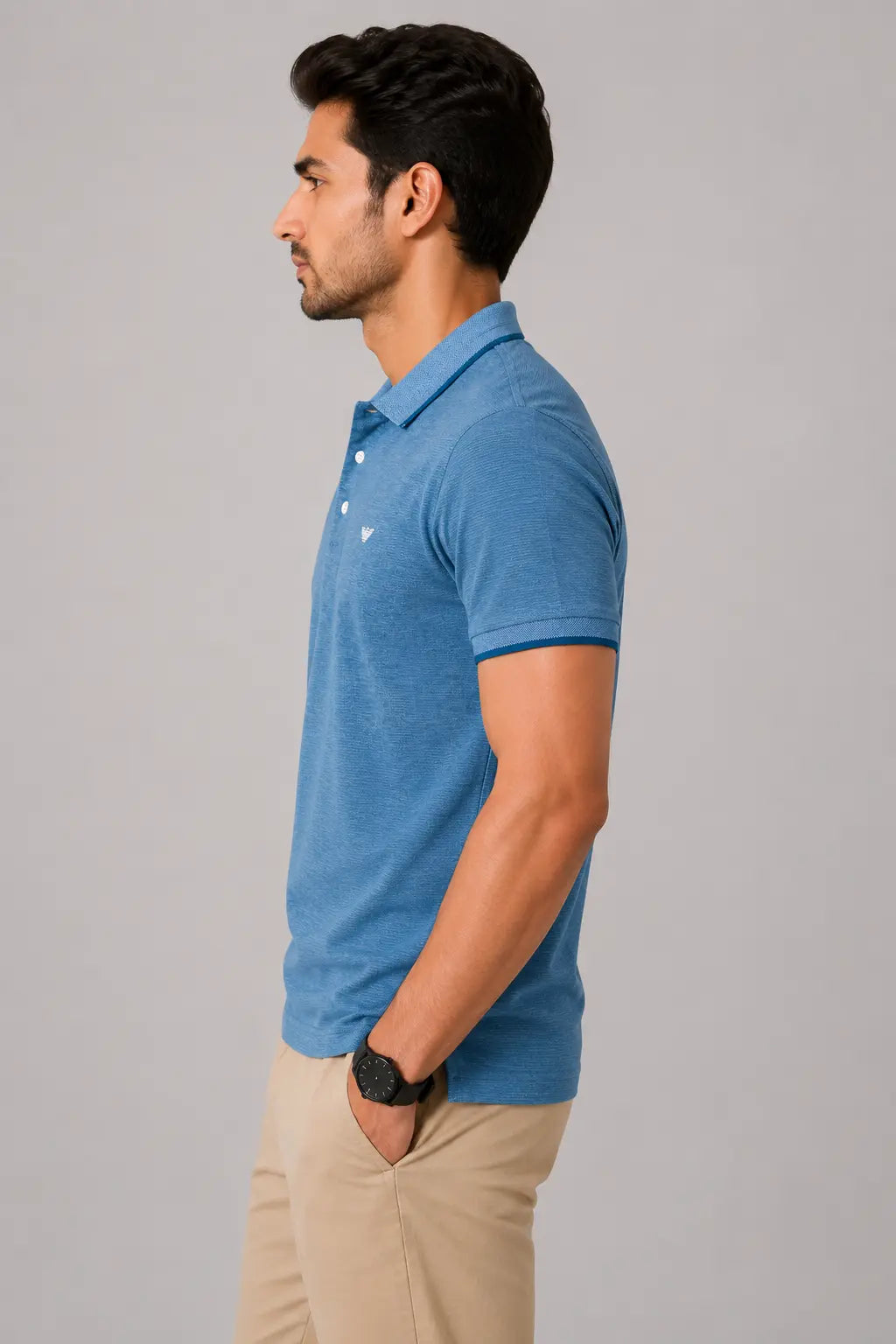 Man wearing a blue polo shirt and beige pants against a gray background
