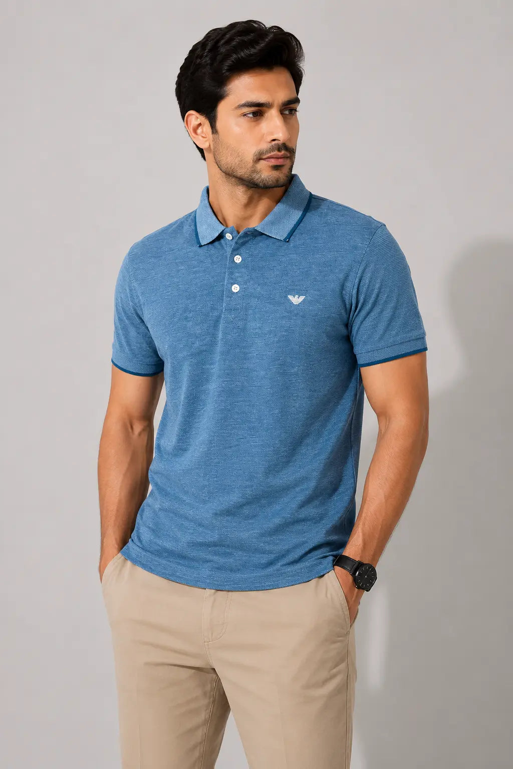 Man wearing a blue polo shirt with a logo on a gray background