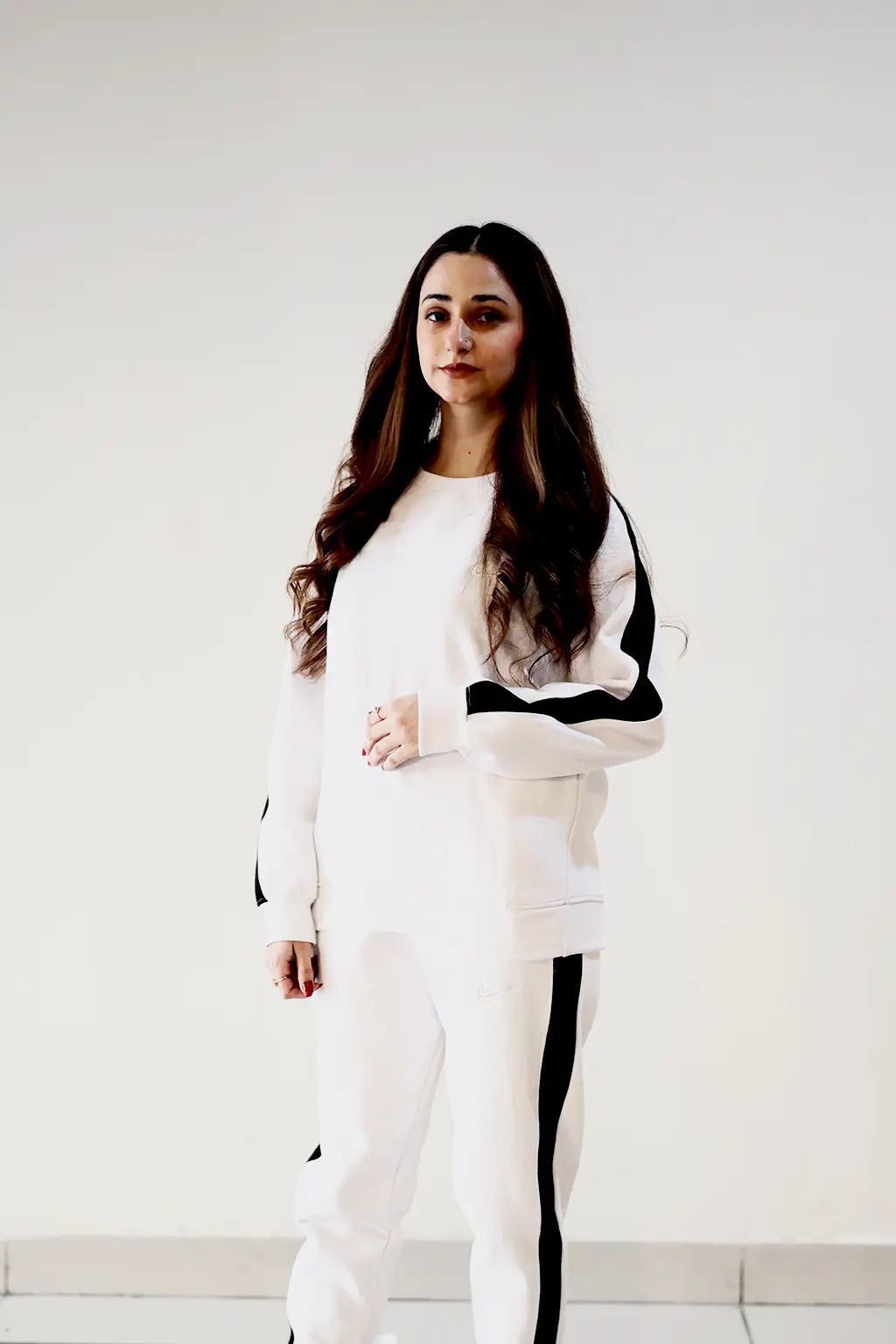 Female Model posing for white winter co-ordset with black border stripes in fleece