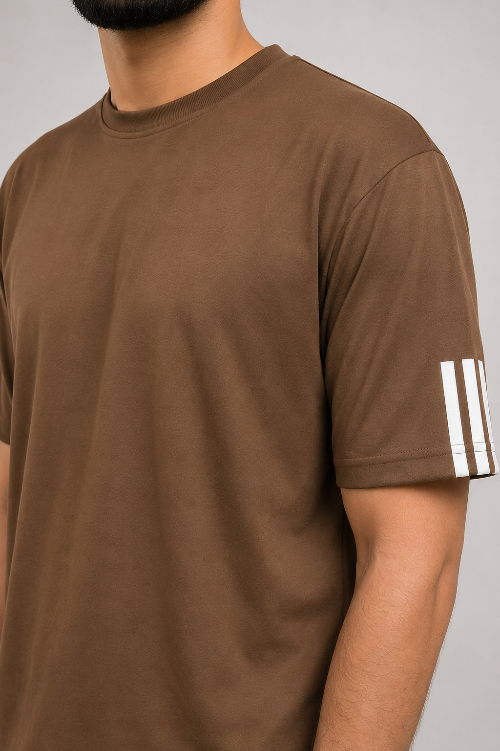 Brown t-shirt with white stripes on sleeve against a neutral background