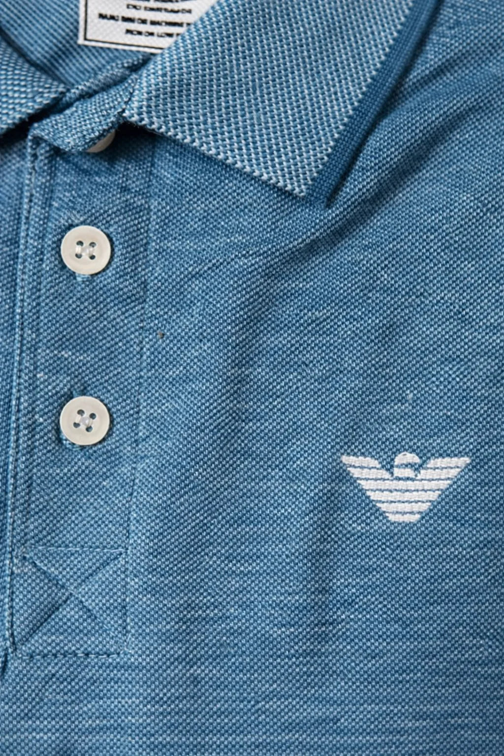 Blue polo shirt with a brand logo on a close-up of the chest area.